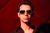 young man in sunglasses against a red wall with dramatic lighting